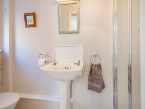 Un baño con lavamanos blanco, espejo, inodoro y ducha.