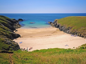 A coastal beach with rocky cliffs, a sandy shore, and a clear blue sea. - 3 bedroom accommodation in Rhoshirwaun, Pwllheli (Rhoshirwaun, Pwllheli)