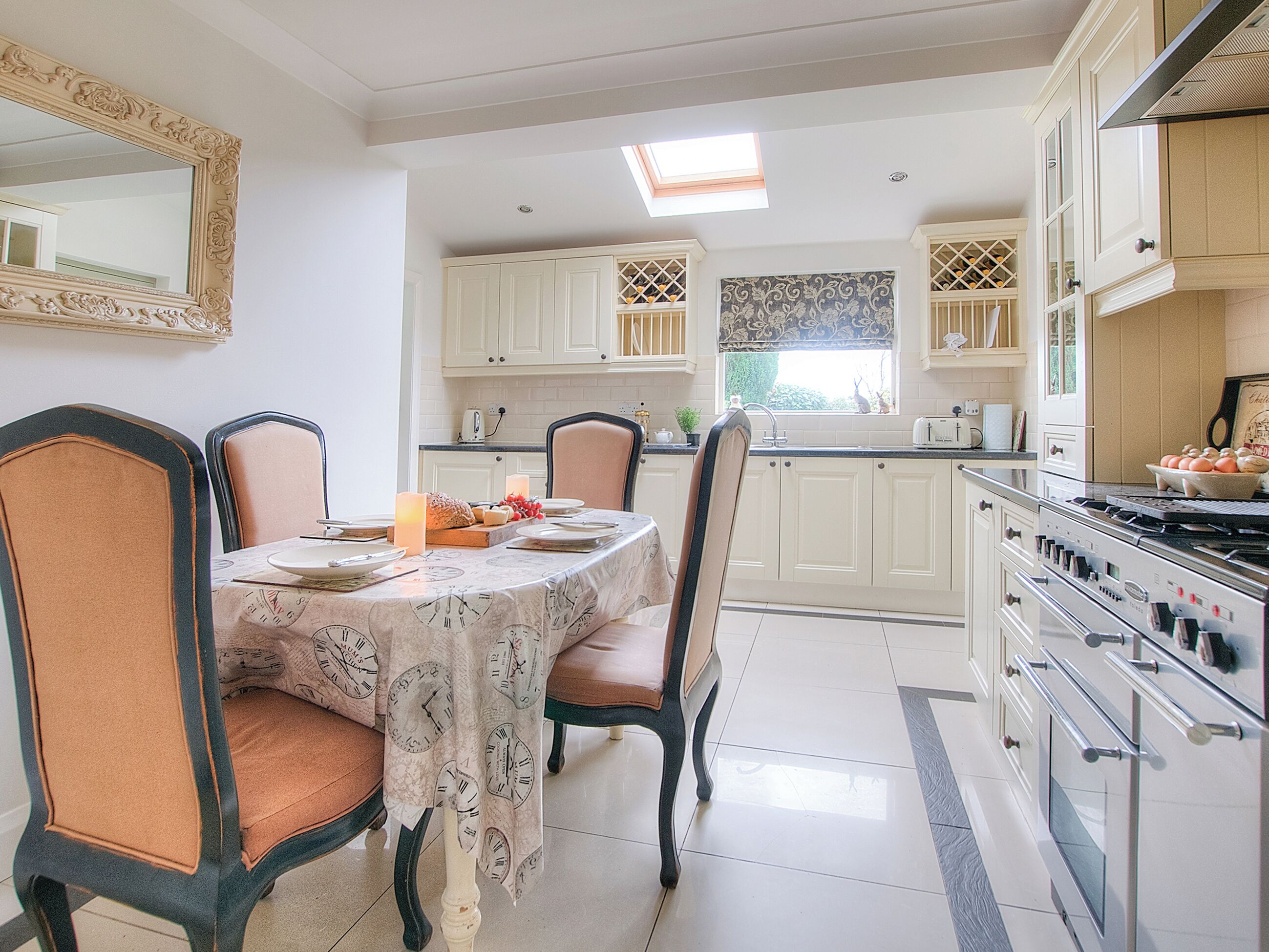 Una cocina con armarios blancos, una mesa de comedor para cuatro personas y una estufa grande.