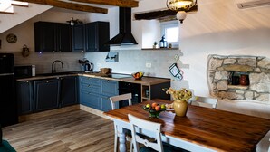 A modern kitchen with dark cabinets, a wooden ceiling, and a stone wall. - Romantic istrian stone house (Pracana, Buzet)