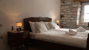 A neatly made bed with white linens, a bedside lamp, and a wooden nightstand. - Romantic istrian stone house (Pracana, Buzet)
