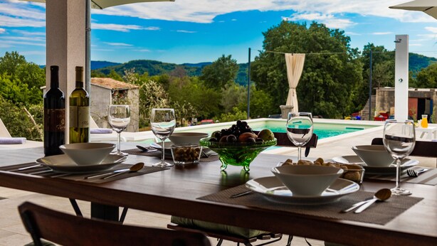 An outdoor dining area with a view of a swimming pool and hills. - Romantic istrian stone house (Pracana, Buzet)