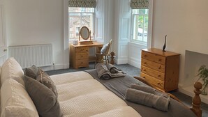 A bedroom with a large bed, wooden dresser, and a vanity with a mirror. - 3 bedroom accommodation in Comrie, near Crieff (Comrie, near Crieff)