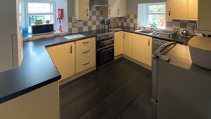 A modern kitchen with a black countertop, white cabinets, and a stainless steel range hood. - 3 bedroom accommodation in Comrie, near Crieff (Comrie, near Crieff)