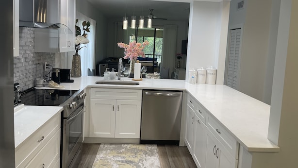 A modern kitchen with white cabinetry, stainless steel appliances, and a central island. - Remodeled, Luxurious 2BR+2Bath by IMG+Beach (Bradenton)