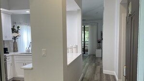 A modern kitchen with white cabinets, a built-in oven, and a countertop with a vase of flowers. - Remodeled, Luxurious 2BR+2Bath by IMG+Beach (Bradenton)