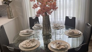 A round glass dining table with six chairs, a vase with pink flowers, and a chandelier. - Remodeled, Luxurious 2BR+2Bath by IMG+Beach (Bradenton)