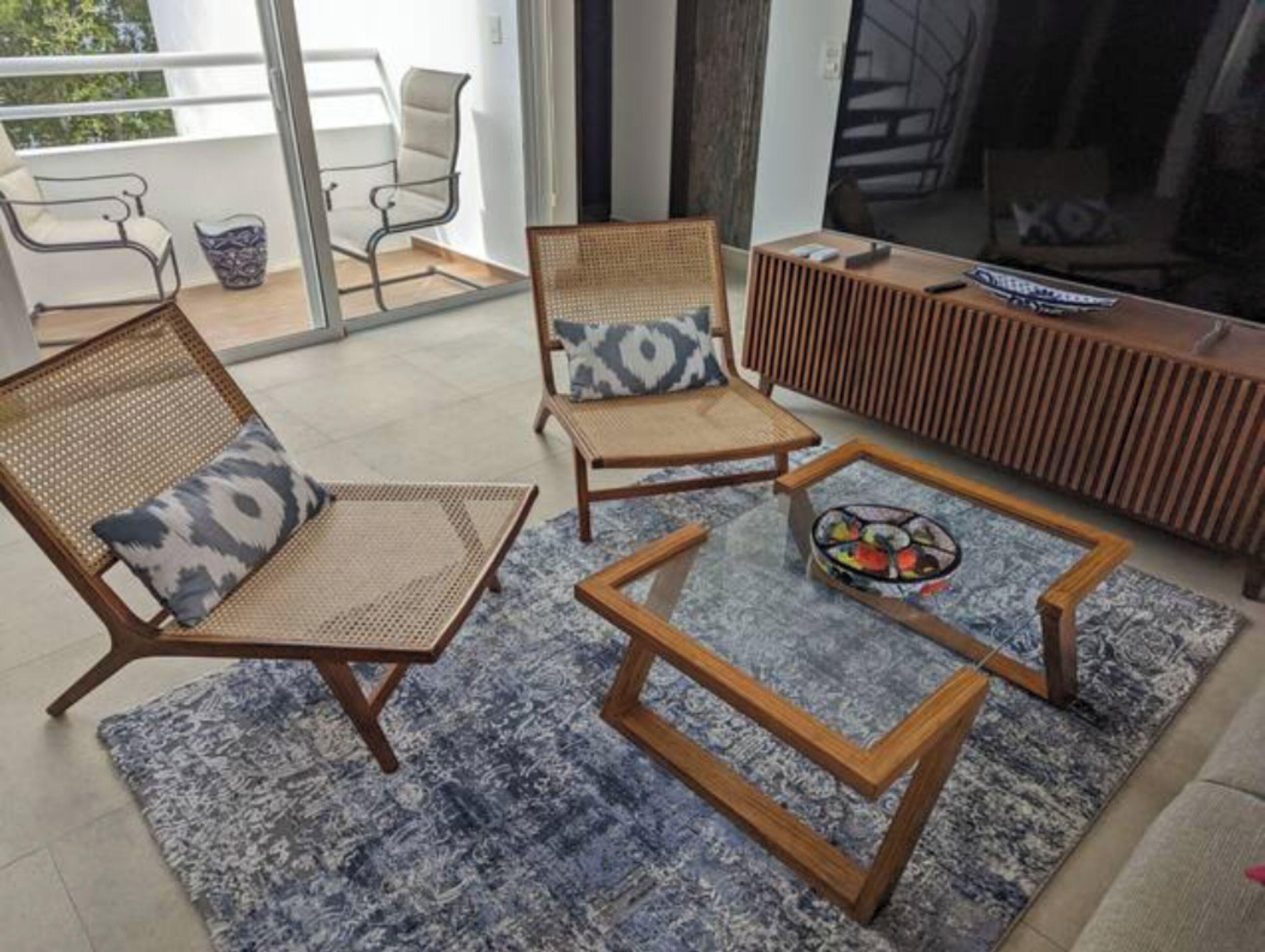 A modern living room with wicker chairs, a coffee table, and a TV stand.