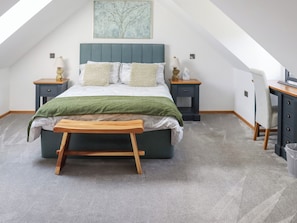 A bedroom with a bed, bedside tables, a desk, a chair, and a bench. - Preselli View Cottage - UK37755 (Ludchurch, near Narberth)