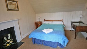 A bedroom with a bed, nightstands, a desk, a fireplace, and a framed picture on the wall. - 2 bedroom accommodation in Kilmaluig, Isle of Skye (Kilmaluig, Isle of Skye)