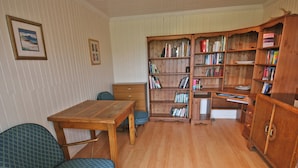 A room with a wooden table, two chairs, a bookshelf, and a dresser. - 2 bedroom accommodation in Kilmaluig, Isle of Skye (Kilmaluig, Isle of Skye)