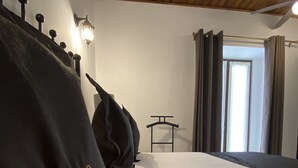 A hotel room with a bed, a nightstand, a lamp, and a window with curtains.