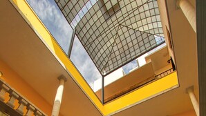 A multi-level atrium with a glass ceiling, red chairs, and a staircase.