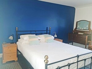 A bedroom with a bed, bedside tables, a dresser, a mirror, and a lamp.