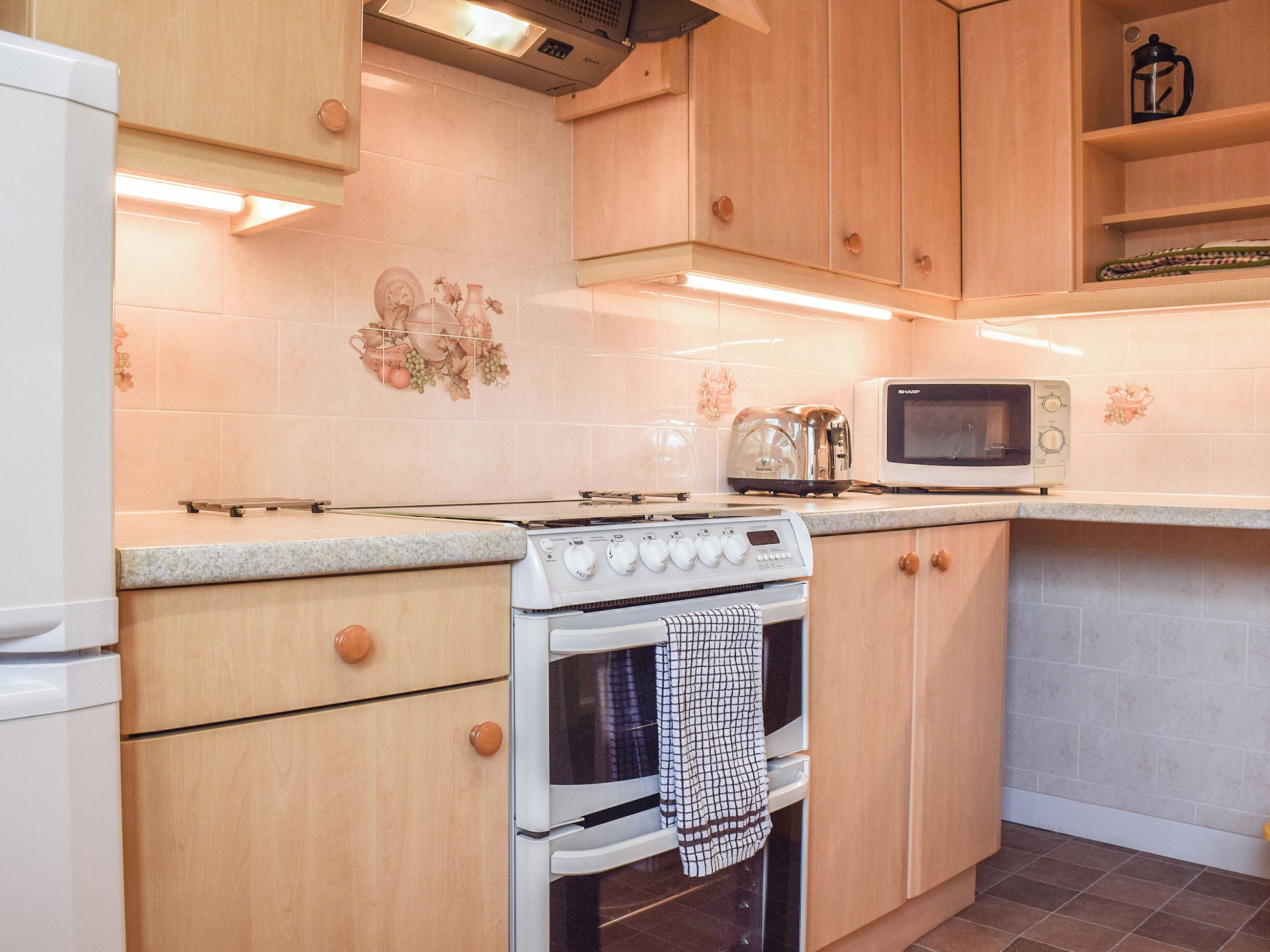 Une cuisine avec des meubles de rangement en bois, une cuisinière blanche, un four à micro-ondes et un grille-pain.