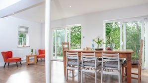 Un coin repas avec une table et des chaises en bois, un radiateur et une fenêtre donnant sur un paysage verdoyant.