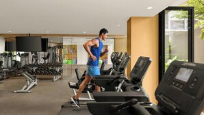 Ein Fitnessstudio mit Laufbändern, Kraftgeräten und einem großen Spiegel.