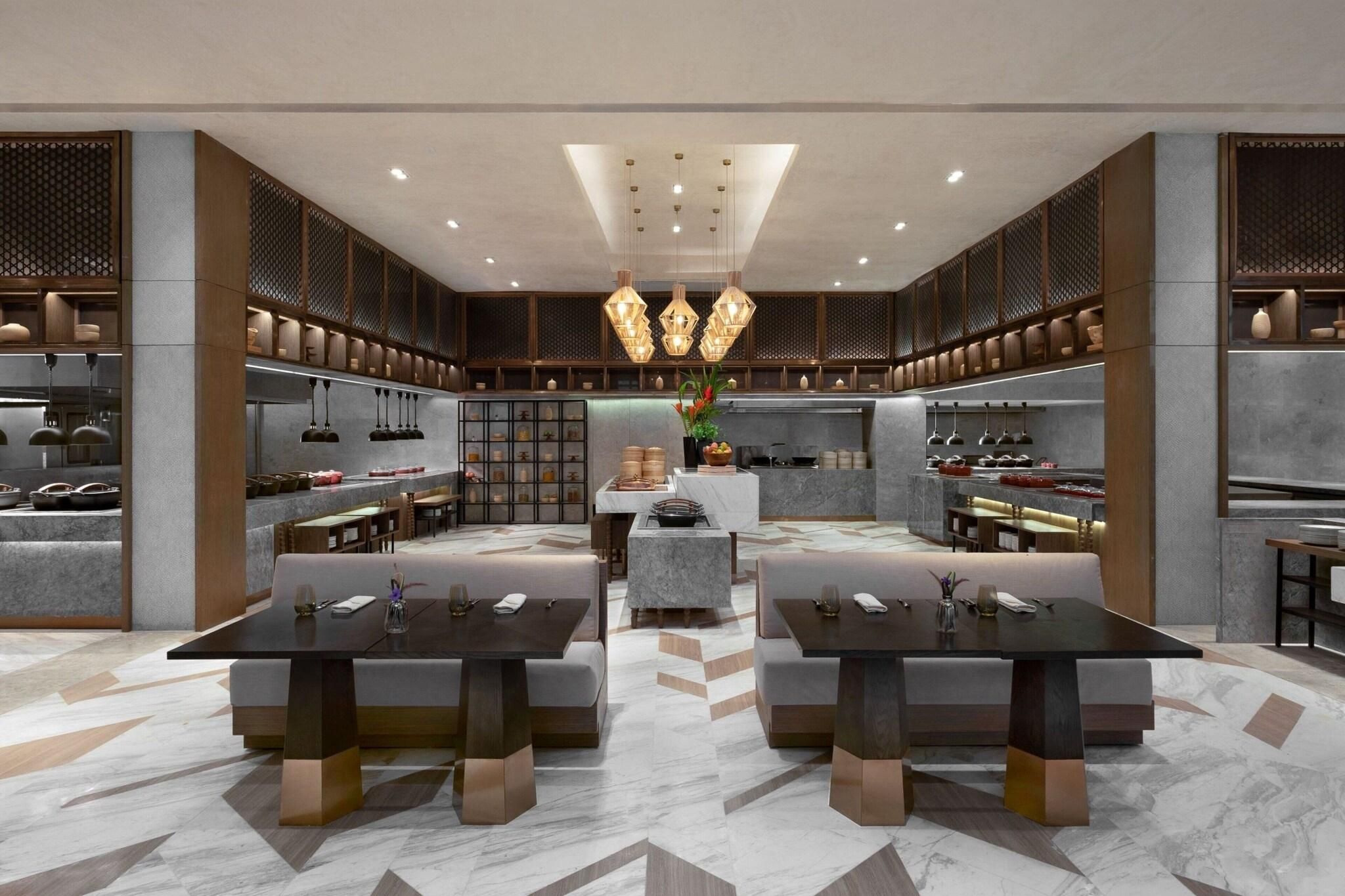 A modern kitchen with a central island, pendant lighting, and built-in shelving.