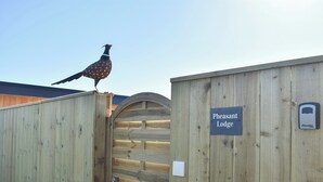 A wooden gate with a sign reading "Pheasant Lodge" and a bird perched on top. - Pheasant Lodge at Wood House (Consett)