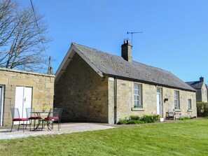 A stone building with a gabled roof, a chimney, and a sign indicating it is a guesthouse.