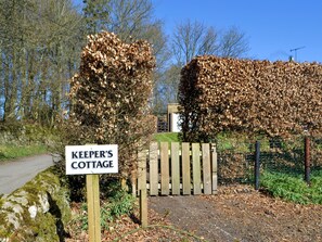 A wooden gate with a sign reading "KEEPER'S COTTAGE" in front of a pile of leaves. - Keepers Cottage Burradon (Burradon near Thropton)