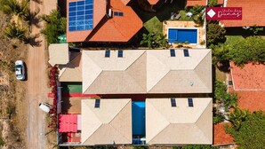 An aerial view of a property with a central building featuring a blue door and solar panels on the roof.
