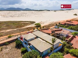 Un hotel costero con varias edificaciones, una playa al fondo y cielo despejado.