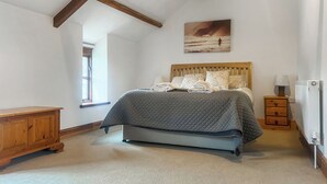 Une chambre à coucher avec un lit, une tête de lit en bois, un tableau, une table de chevet, une lampe et un radiateur.
