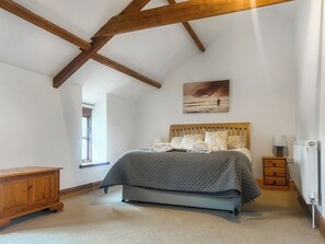 Ein Schlafzimmer mit Bett, Holz-Kopfteil, einem Gemälde, einem Nachttisch, einer Lampe und einer Heizung.