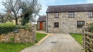Une maison en pierre avec une allée gravillonnée, un portail en bois et une enseigne indiquant « The Granary ».