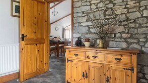 Un meuble en bois avec des tiroirs, un mur en pierre et un coin repas avec une table et des chaises.