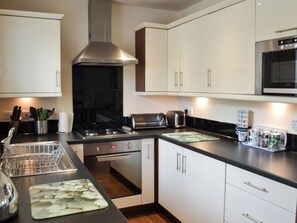 A modern kitchen with white cabinets, stainless steel appliances, and a black countertop.