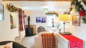 Una habitación acogedora con chimenea, un sofá, una cama y adornos festivos.