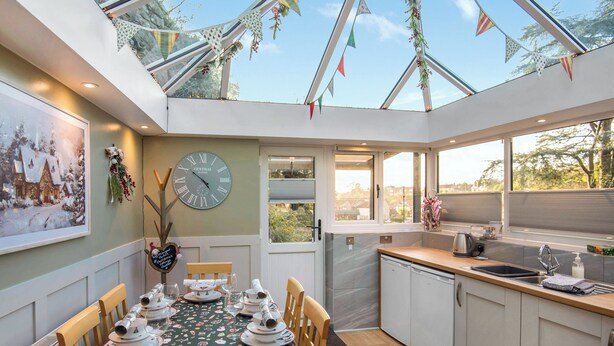 Una cocina moderna con comedor, que presenta un reloj grande, decoraciones festivas y vistas al exterior.