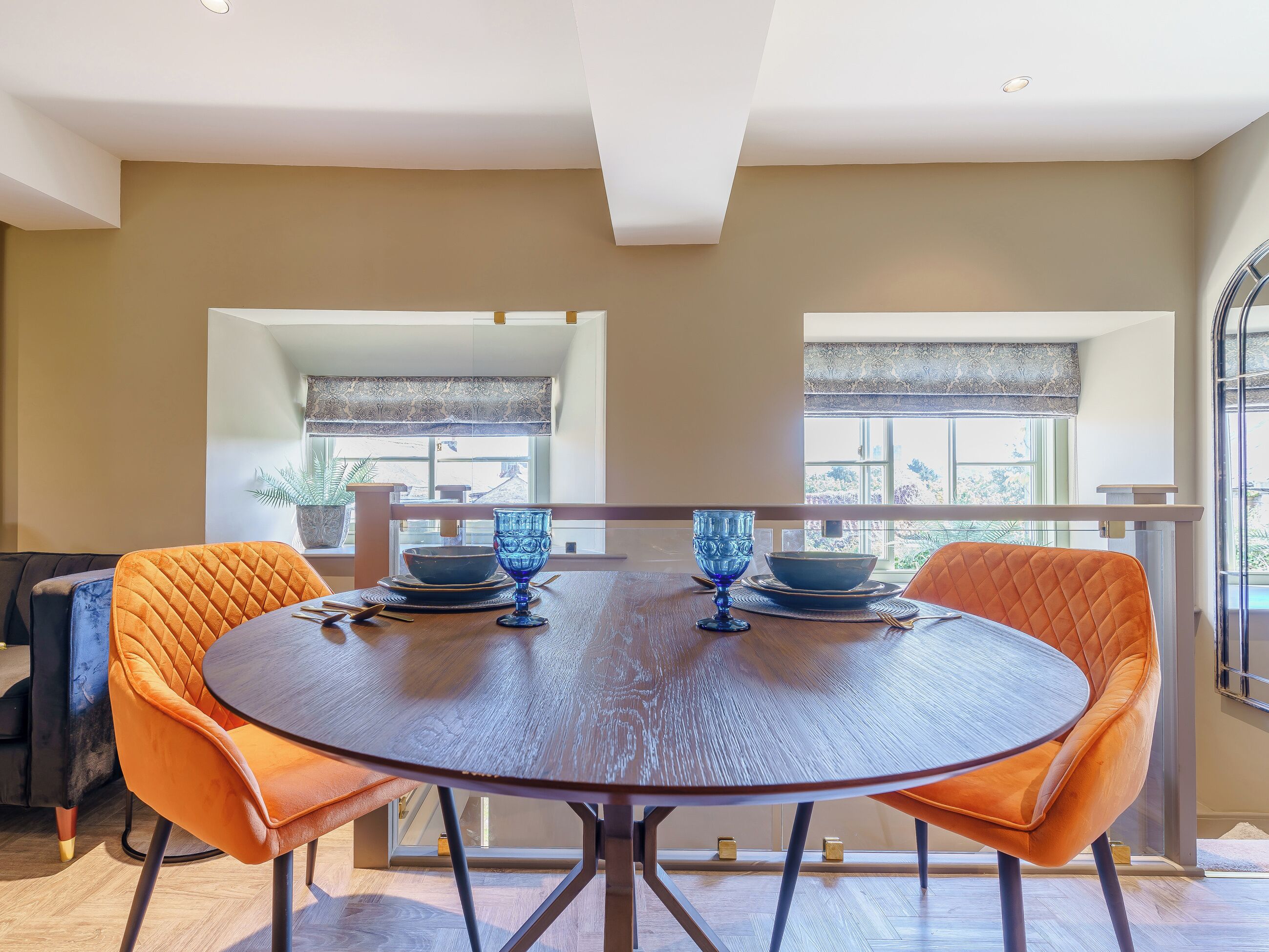 Un coin repas avec une table ronde, deux chaises et un verre bleu.