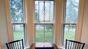 Une pièce d’angle avec trois fenêtres, une table en bois et deux chaises.