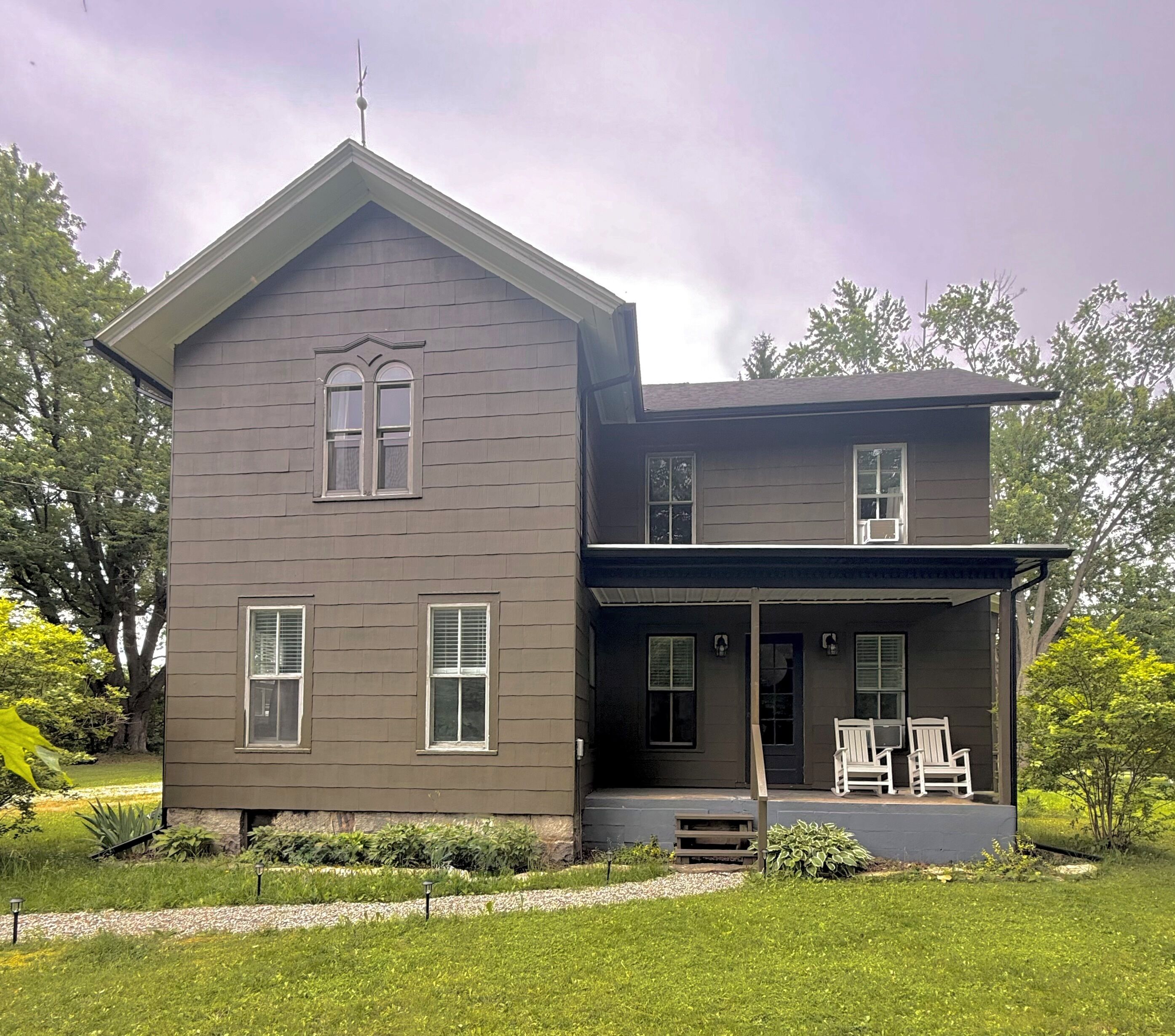 A two-story house with a porch, a chimney, and a satellite dish.