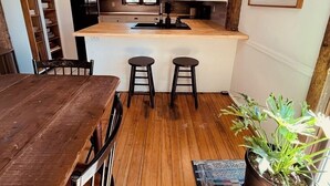 Une cuisine avec des poutres en bois, un îlot central avec des tabourets et une table à manger avec des chaises.