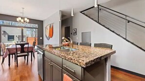 Uma cozinha moderna com bancadas de granito, forno embutido e pia de aço inoxidável.