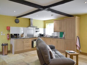 A kitchen with a sofa, wooden cabinets, a microwave, and a fire extinguisher.