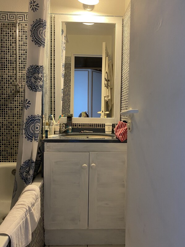 Ein Badezimmer mit einem weißen Waschtisch, einem Spiegel und einer Badewanne.