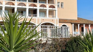 A multi-story hotel with a central courtyard, featuring balconies with lattice railings and a sign for a snack bar. - Ideally located 4-person apartment with exceptional view (Saint-Raphaël)