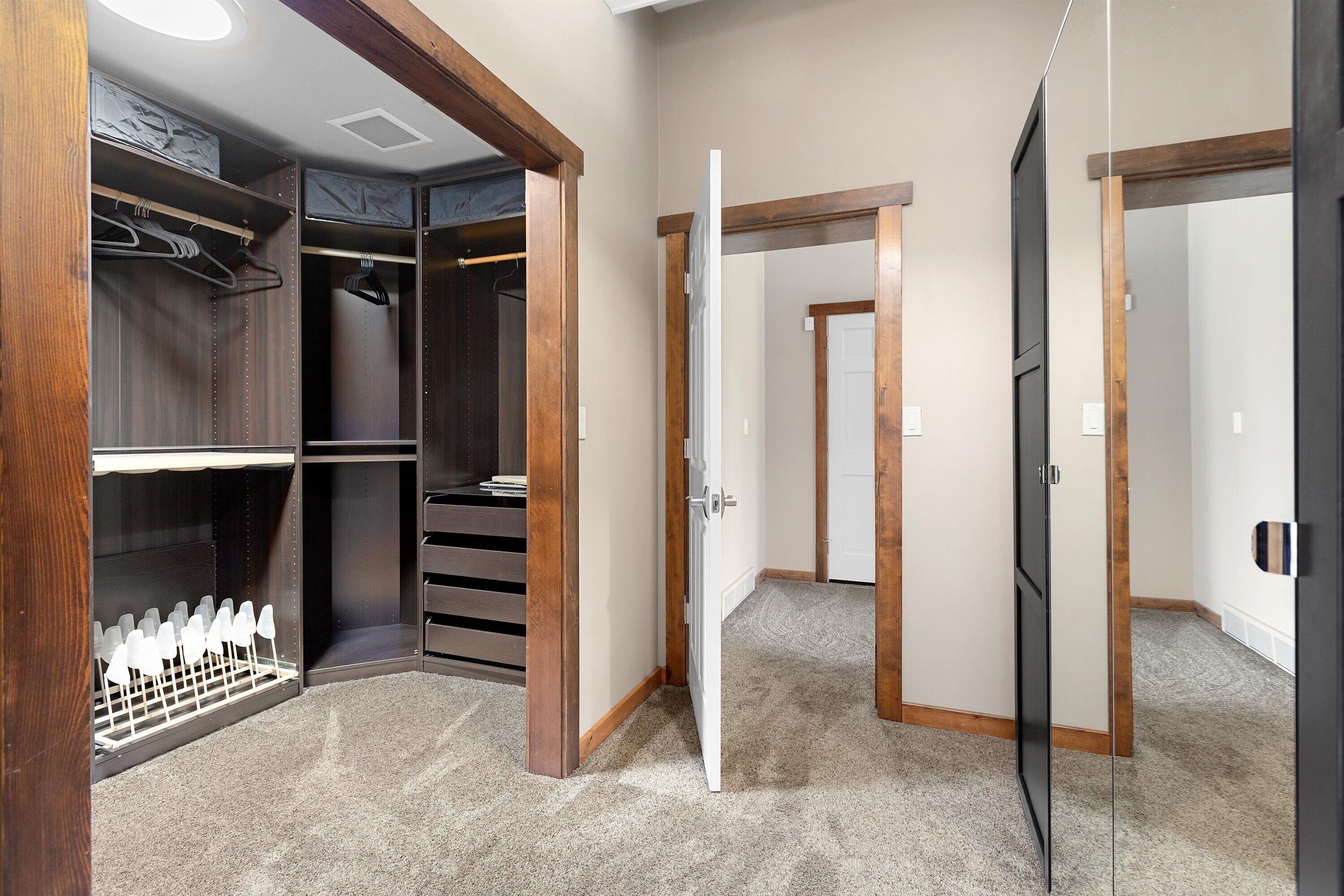 A walk-in closet with multiple shelves and hanging space, a shoe rack, and a door leading to another room.