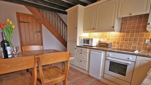 Une cuisine équipée de chaises en bois, d’une table à manger, d’un four à micro-ondes, d’un lave-vaisselle et d’une cuisinière.