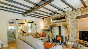 A cozy living room with a stone fireplace, a sofa, and a staircase leading to another room. - 3 bedroom accommodation in Bewerley, near Pateley Bridge (Bewerley, near Pateley Bridge)