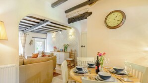 A dining area with a wooden table set for four, white chairs, and a wall clock. - 3 bedroom accommodation in Bewerley, near Pateley Bridge (Bewerley, near Pateley Bridge)