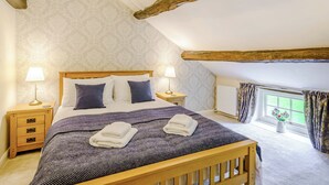 A bedroom with a wooden bed, two bedside tables with lamps, a window with curtains, and a radiator. - 3 bedroom accommodation in Bewerley, near Pateley Bridge (Bewerley, near Pateley Bridge)