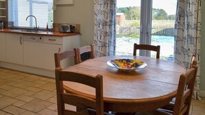 A kitchen with a dining table and chairs, a sink, and a window with blinds. - 3 bedroom accommodation in Newton by the Sea (Newton by the Sea)