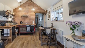 Una cocina con piso de madera, una isla central, iluminación colgante y un ventanal grande.