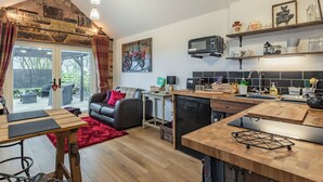 Una cocina acogedora con pared de piedra, techo de madera y un rincón comedor con alfombra roja.